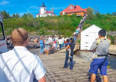 A group Raspberry Island Lighthouse tour disembarks and climbs ups steps to begin their guided tour of the site.